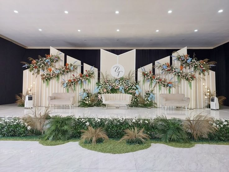 a stage set up for a wedding with flowers and greenery on the sidelines