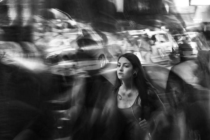 black and white photograph of people walking down the street with blurry image behind them