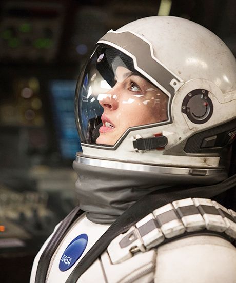 a woman in a space suit and helmet looks off into the distance with her eyes closed