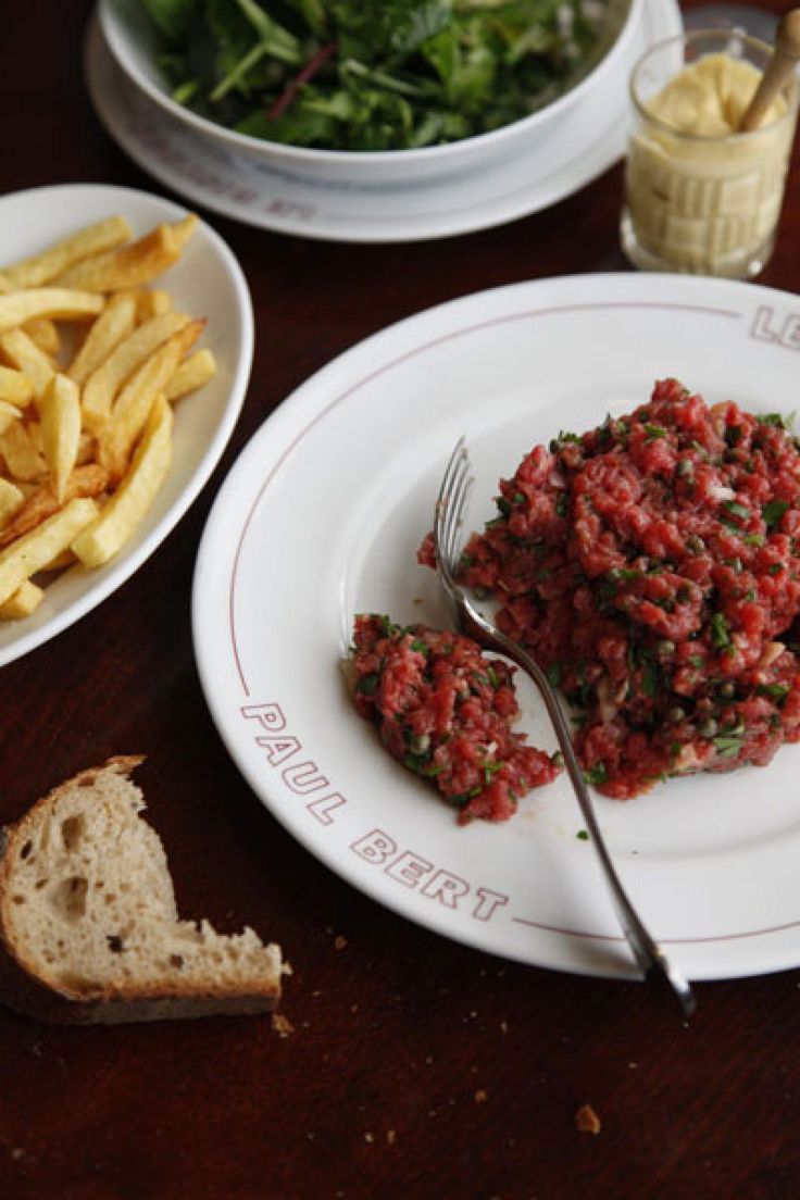 there is a plate of food on the table with french fries and salad next to it