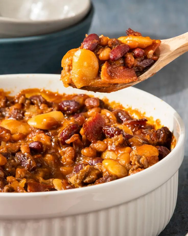 a white bowl filled with beans and other food on top of a blue tablecloth