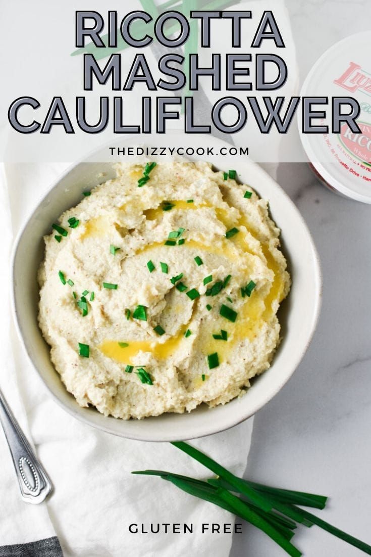 a white bowl filled with mashed cauliflower and topped with green chives