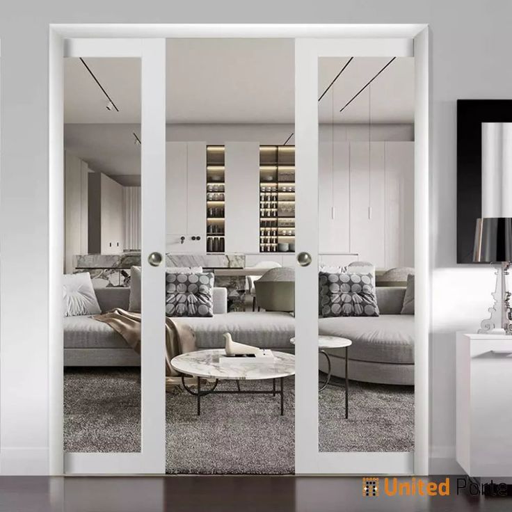 a living room with white furniture and glass doors leading to another room that has a couch