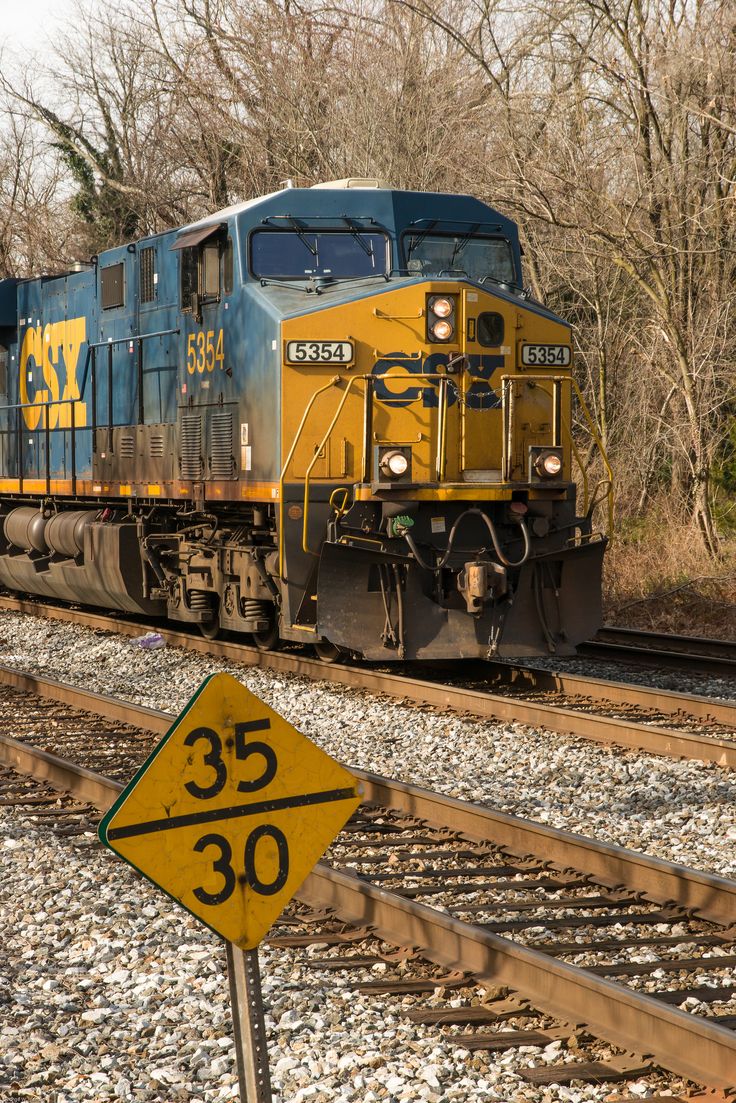 a blue and yellow train traveling down tracks next to a sign that reads 30 cents