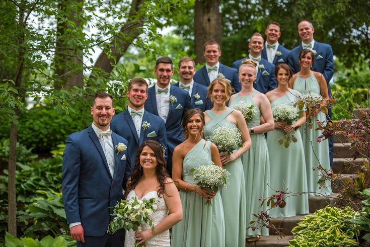 a group of people standing next to each other in front of some trees and bushes