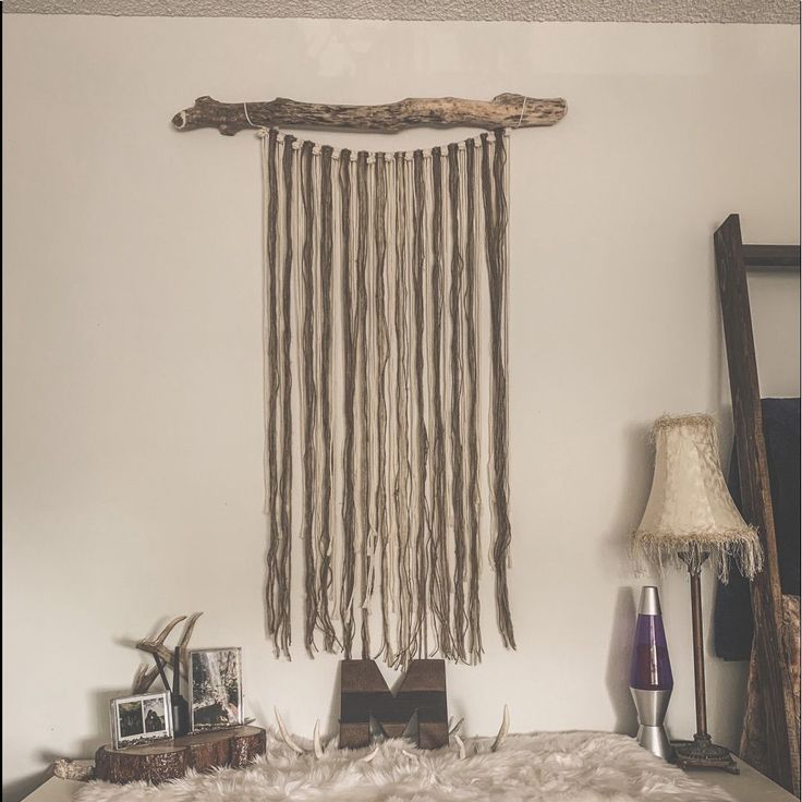 a room with a bed, lamp and wall hanging made out of driftwood sticks