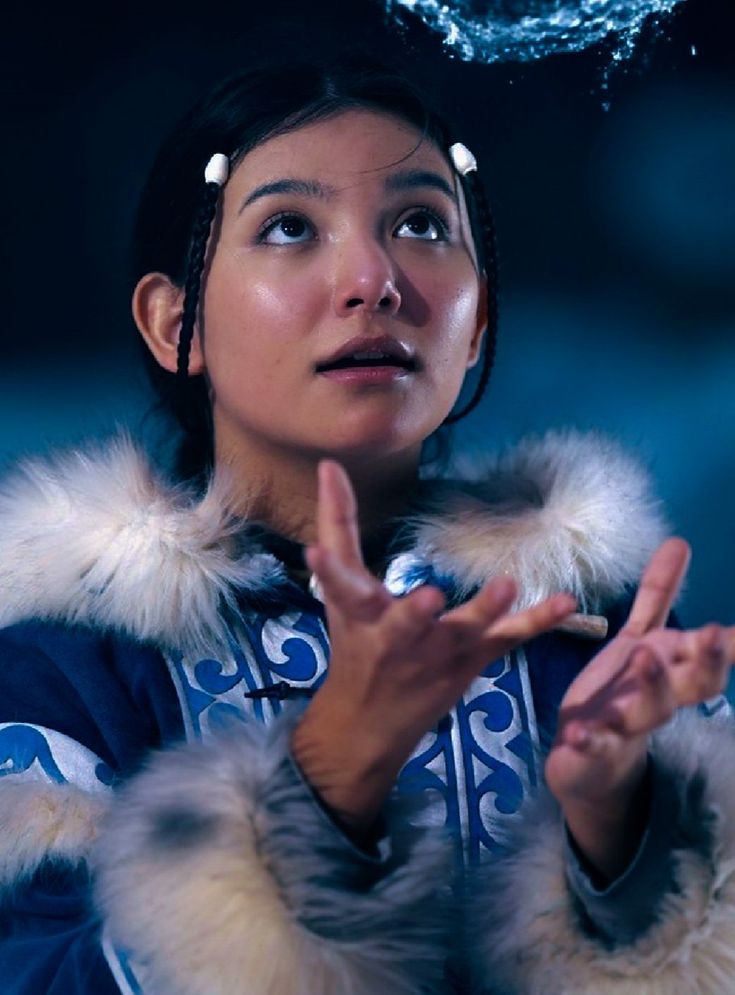 a woman wearing a blue coat and holding her hands up