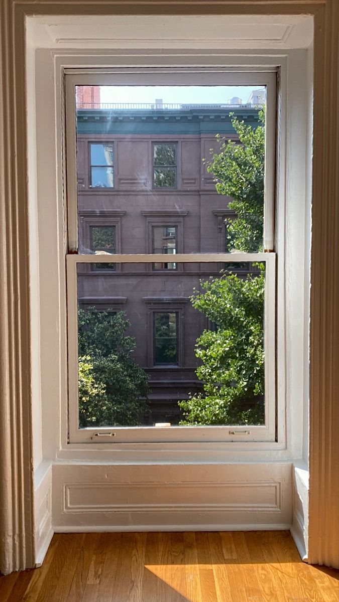 an empty room with a large window and wooden floors in front of the windowsill