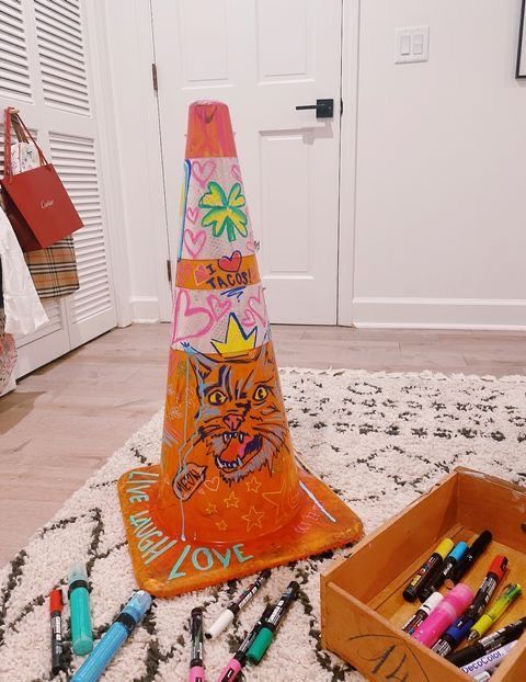 an orange traffic cone sitting on top of a white rug next to markers and pens