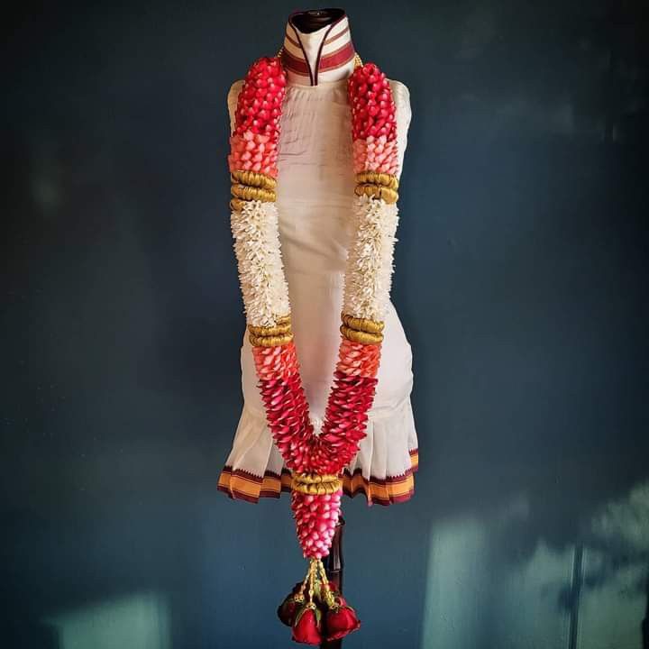 a mannequin dressed in red, white and gold with beads on it's neck