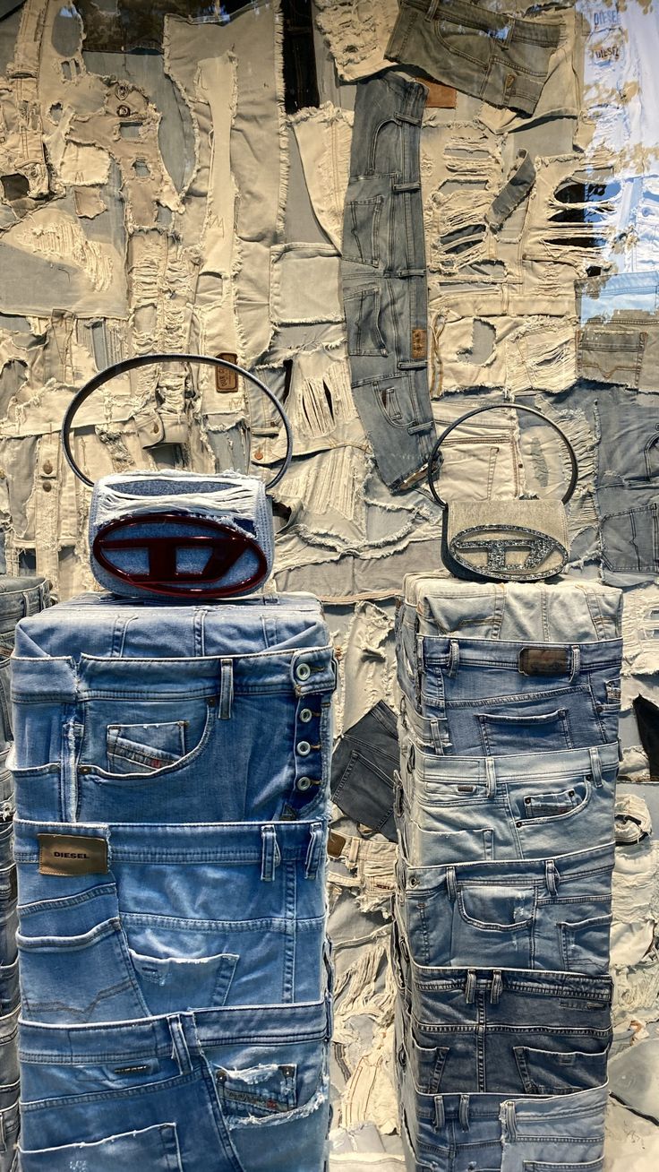 several pairs of jeans are stacked on top of each other in front of a wall