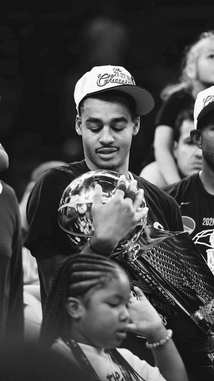 a black and white photo of a young man holding a ball in his hands while people watch