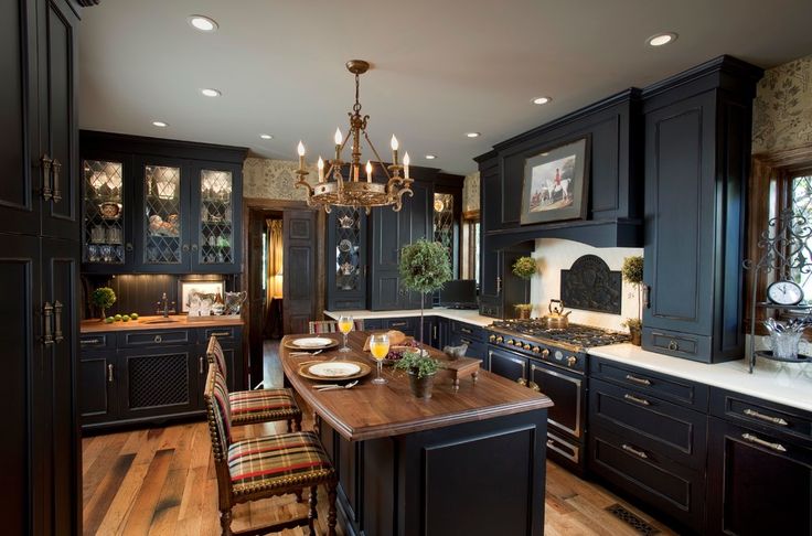 a large kitchen with black cabinets and wooden flooring, along with a dining room table set for four