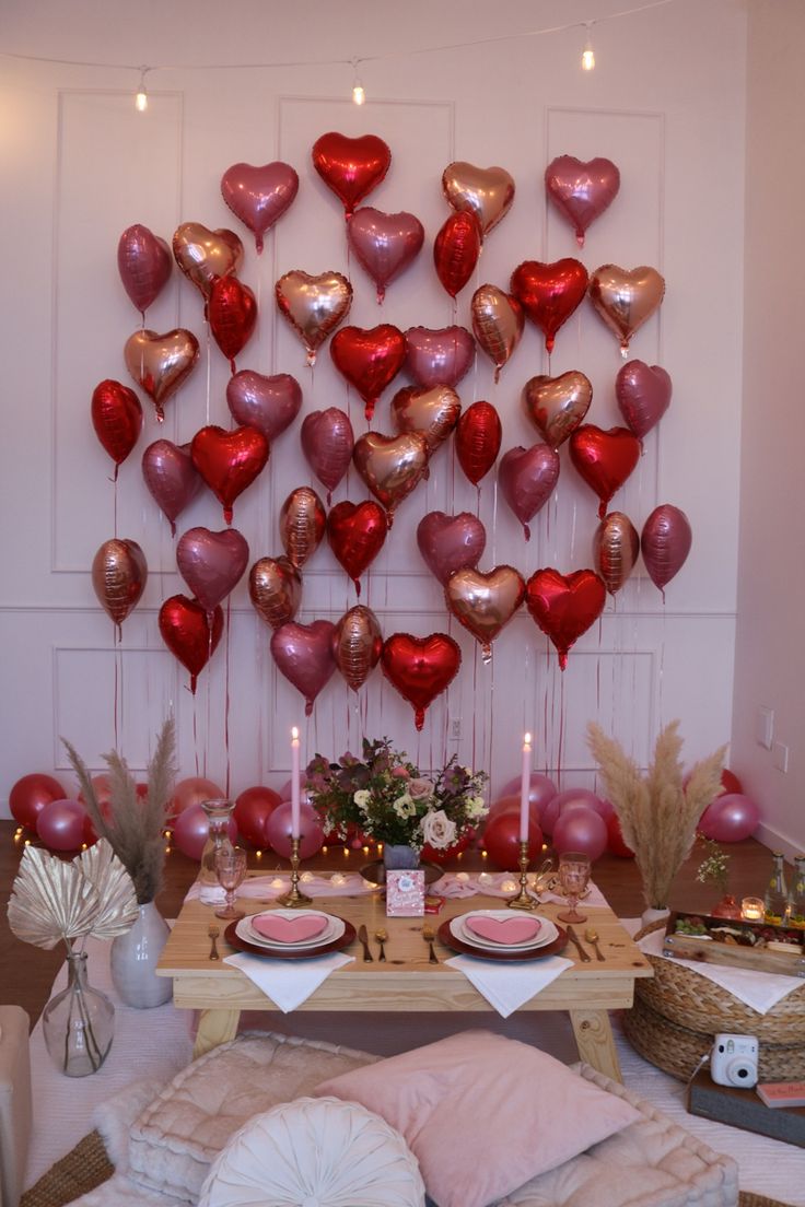 valentine's day table setting with heart balloons on the wall and candles in vases