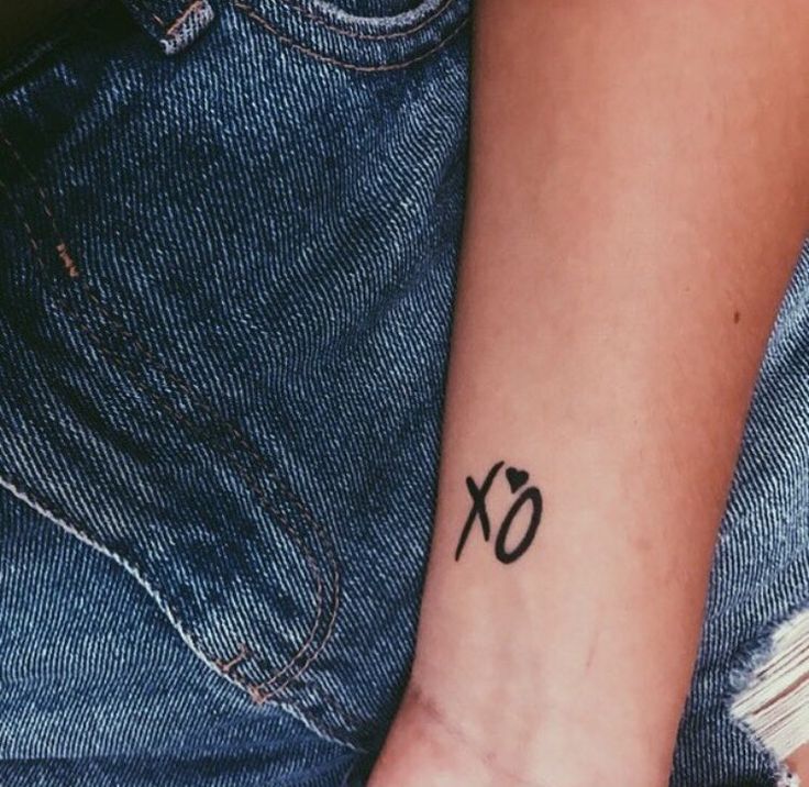 a person with a small tattoo on their arm and the word xo written in black ink