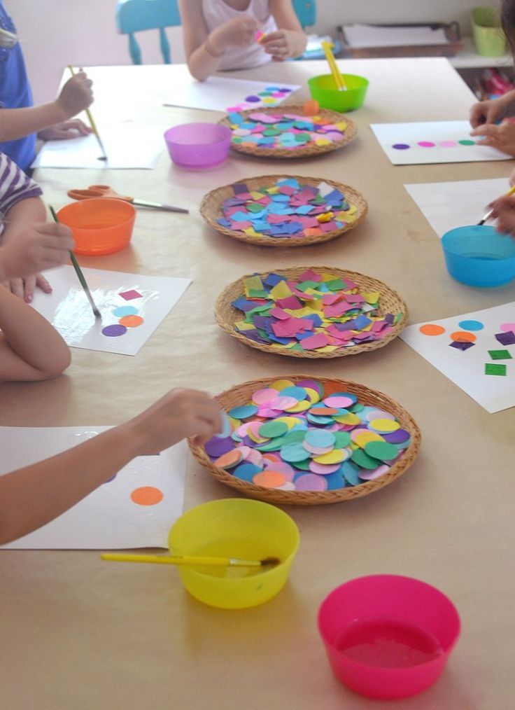 children are sitting at a table making crafts with paper plates and bowls on the table