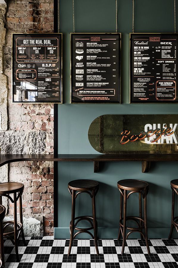 the menus are hanging on the wall behind the bar stools in the restaurant