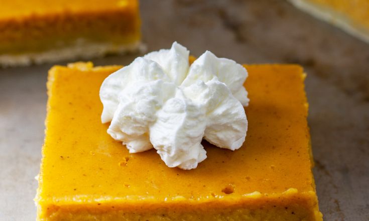 four slices of pumpkin pie with whipped cream on top, sitting on a countertop