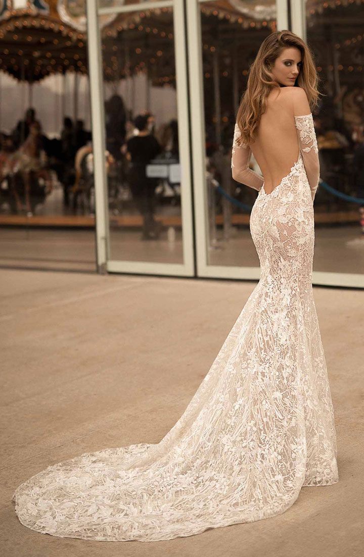 a woman in a wedding dress looking at the back of her long sleeved gown