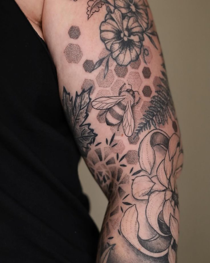 a woman's arm with flowers and a bee on it, in black and white