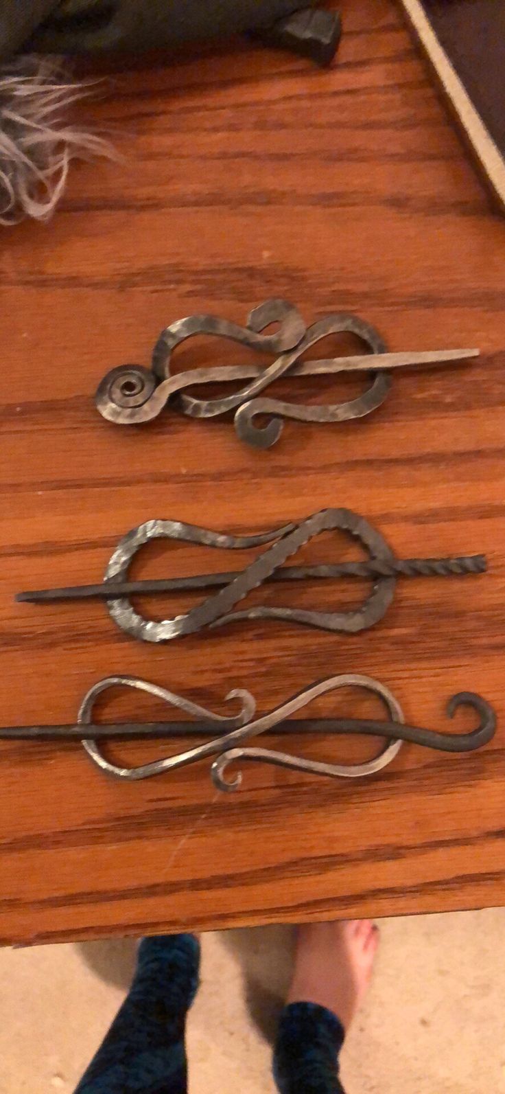 three pairs of scissors sitting on top of a wooden table next to someone's feet