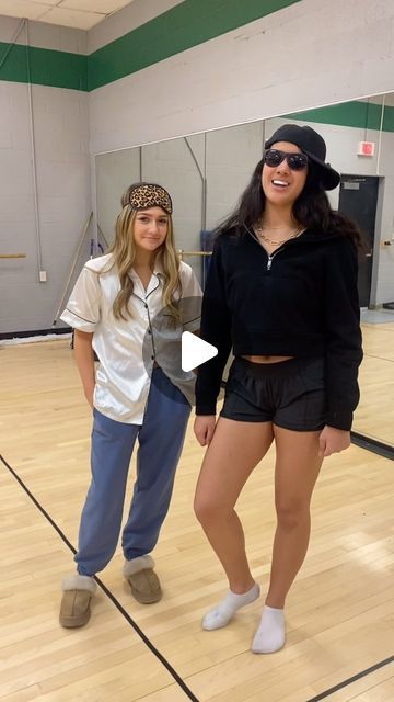 two young women standing on top of a hard wood floor in front of a basketball court