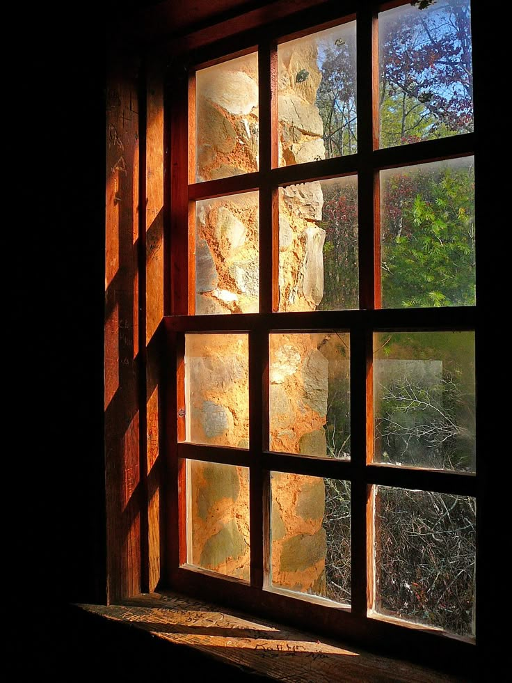 an open window in a dark room with sunlight coming through the windows and trees outside