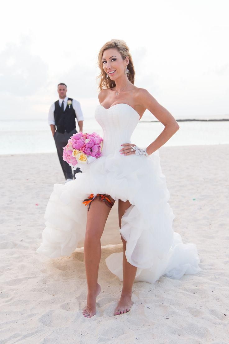 a woman in a white wedding dress standing on the beach next to a man wearing a tuxedo