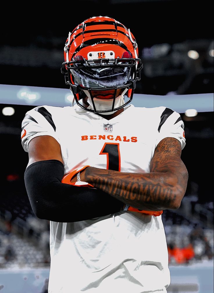 a football player wearing an orange and white uniform with his arms crossed in front of him