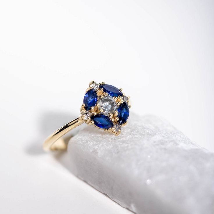 a blue and white diamond ring sitting on top of a rock