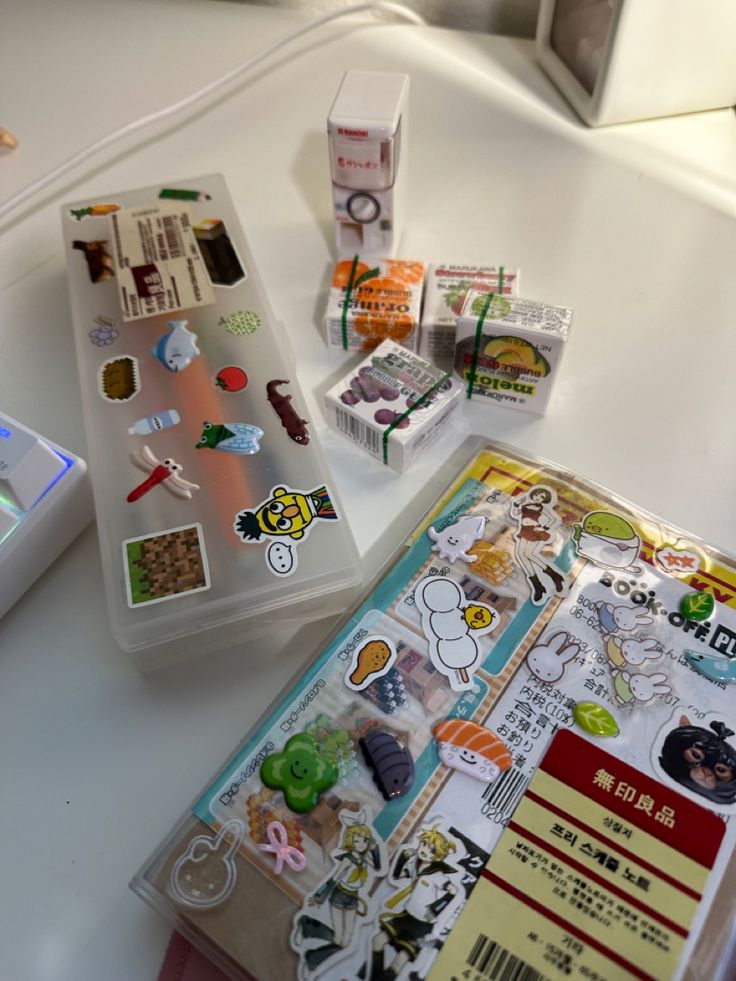 various stickers are sitting on top of a table next to an open book and video game controller