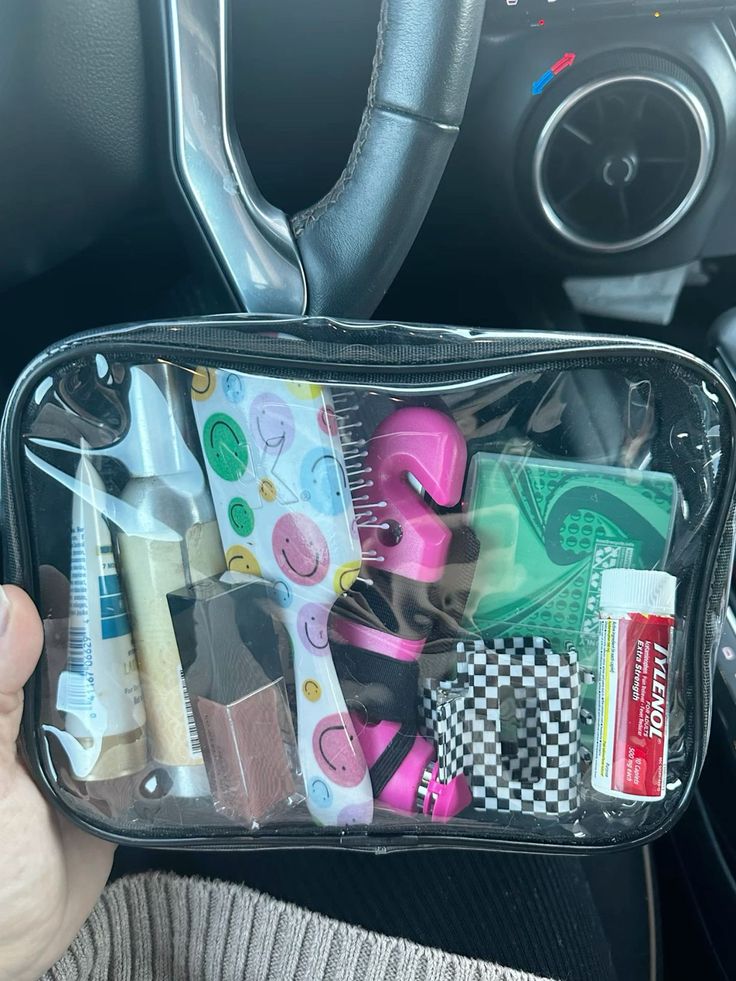 a person holding a clear bag filled with various items in their car's dashboard