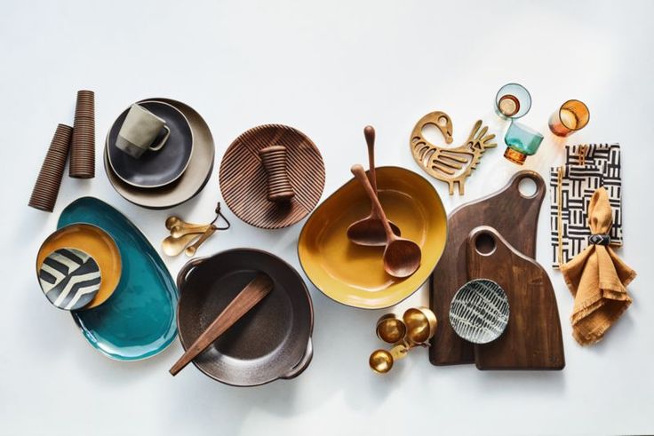 an assortment of dishes and utensils are arranged on a white surface with gold accents