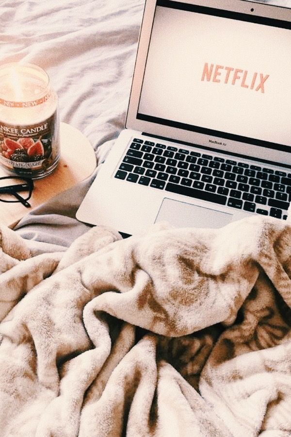 an open laptop computer sitting on top of a bed next to a cup of coffee