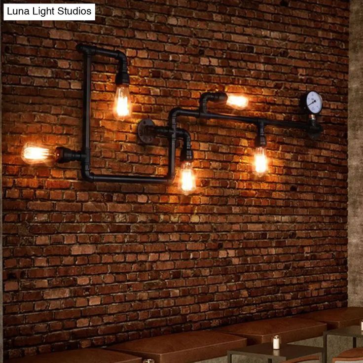 a brick wall with lights on it and some benches in front of it next to a clock