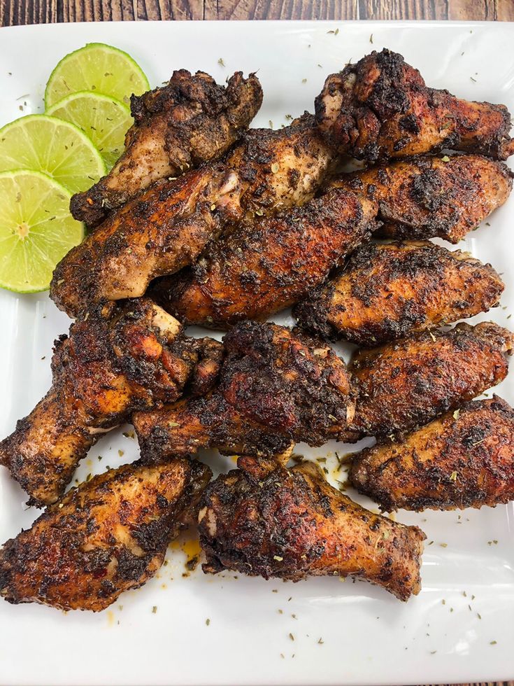 chicken wings with lime wedges on a white plate