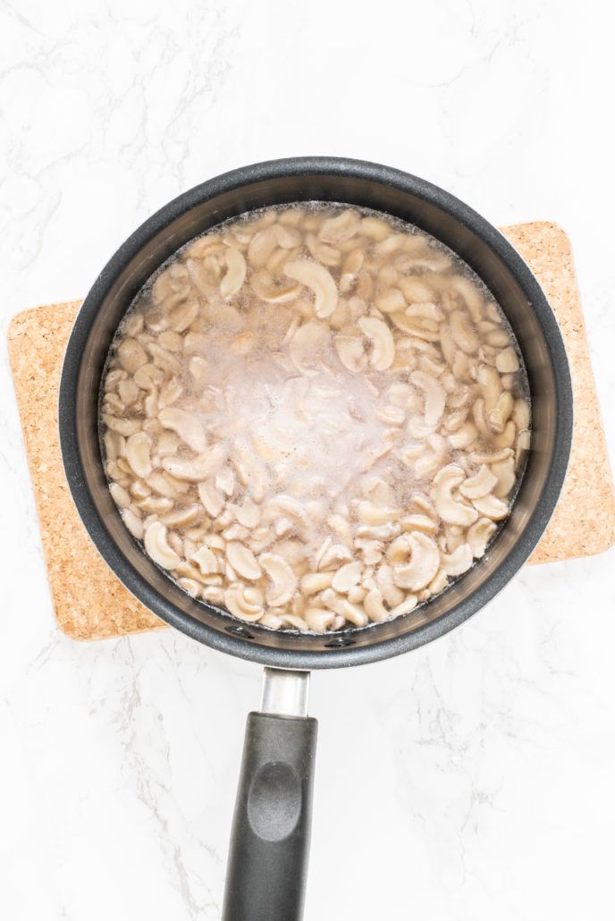 a skillet filled with food on top of a white counter next to a cutting board