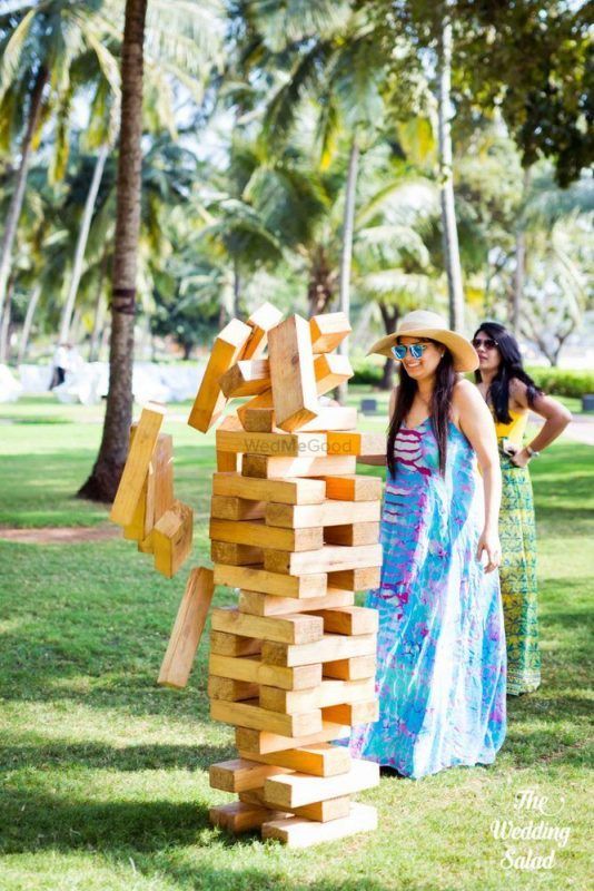 two women standing next to each other near a sculpture made out of wooden blocks in the grass