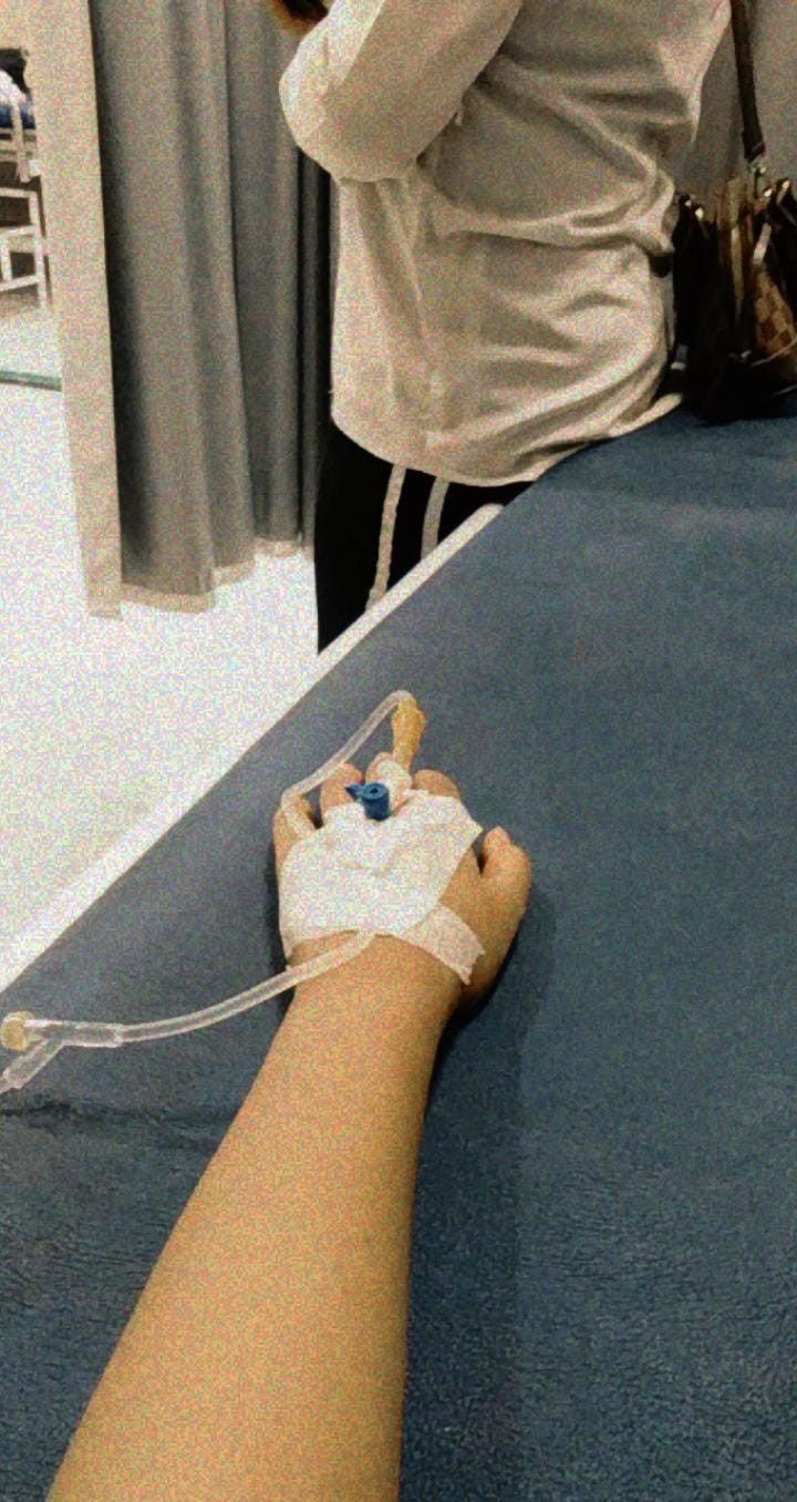 a person with an iv attached to their arm in a hospital room next to a table