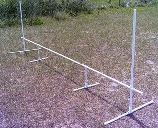 two white poles in the middle of a field with grass and bushes behind them on either side