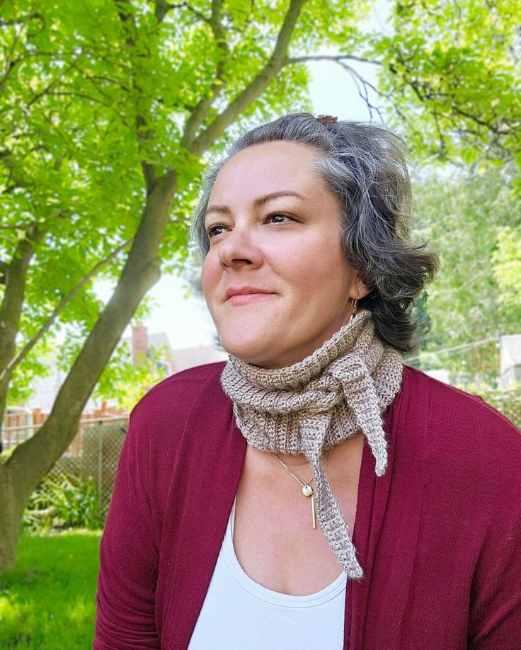 a woman with grey hair wearing a red cardigan and a scarf around her neck