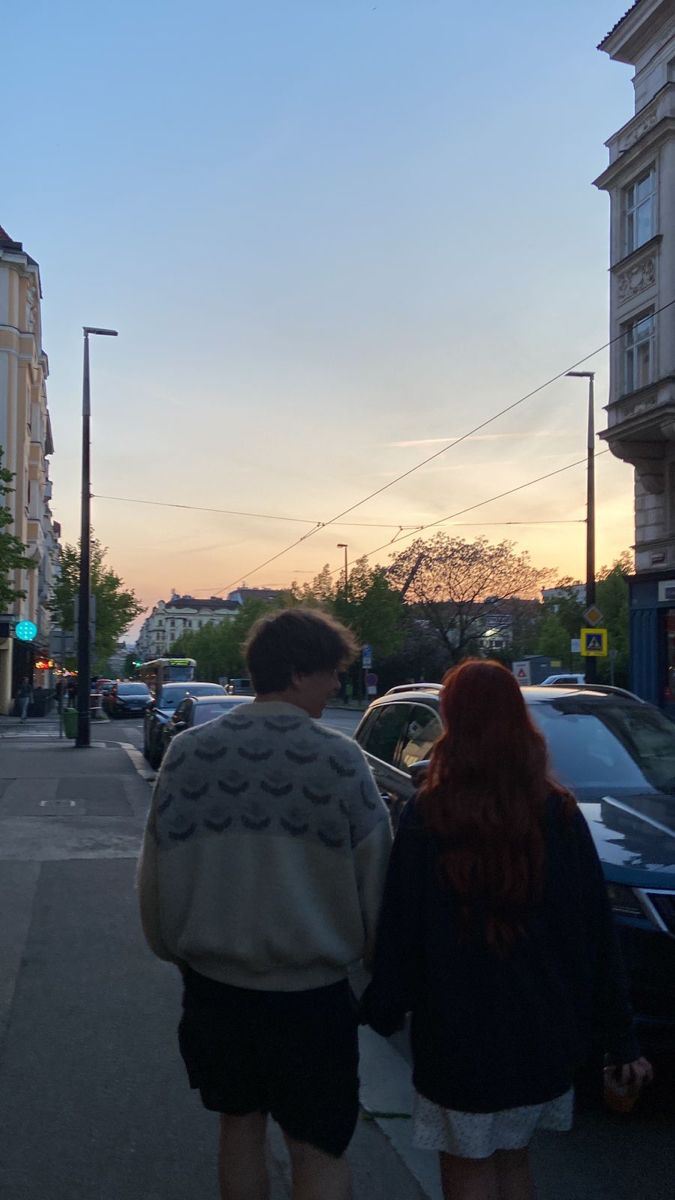 two people walking down the street at sunset