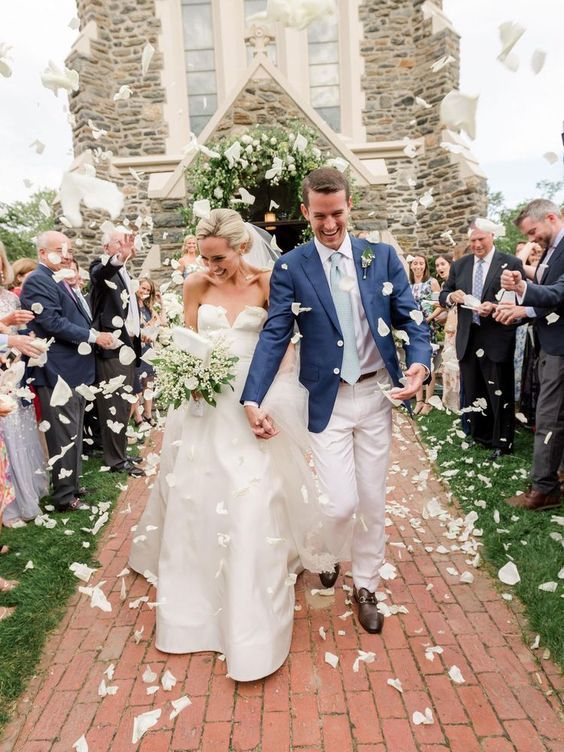 a bride and groom are walking down the aisle as confetti is thrown around them