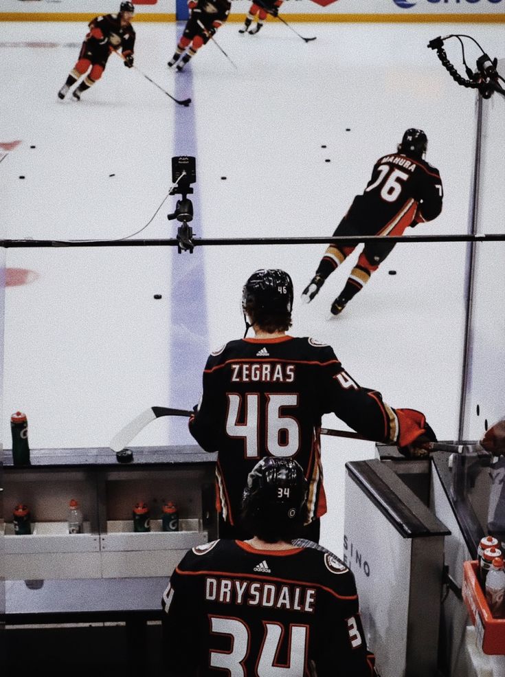 two hockey players sitting on the bench in front of an ice rink