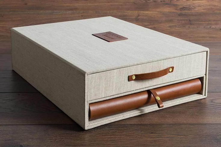 an open box with leather handles on a wooden floor