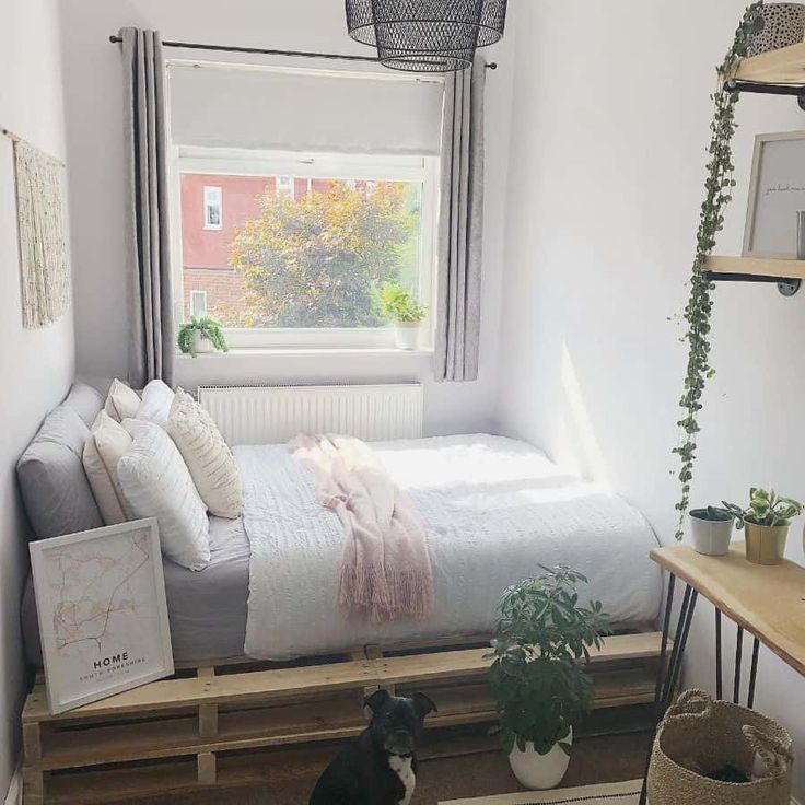 a bedroom with a bed made out of wooden pallets and plants in the window