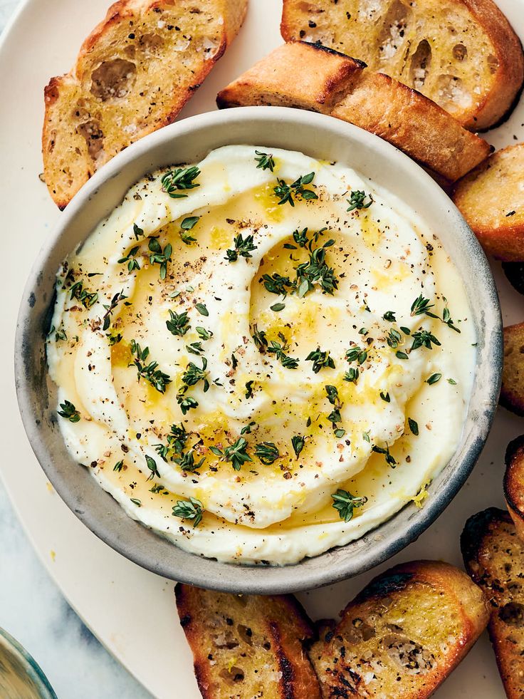 a plate topped with bread and an egg in a bowl surrounded by other food items