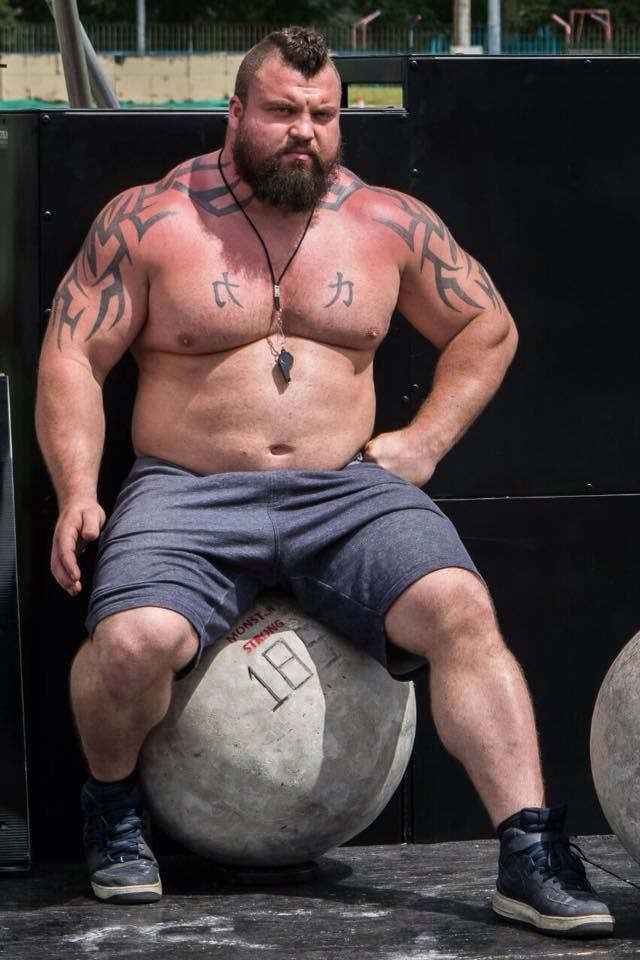 a shirtless man sitting on top of a soccer ball with his hands behind his back