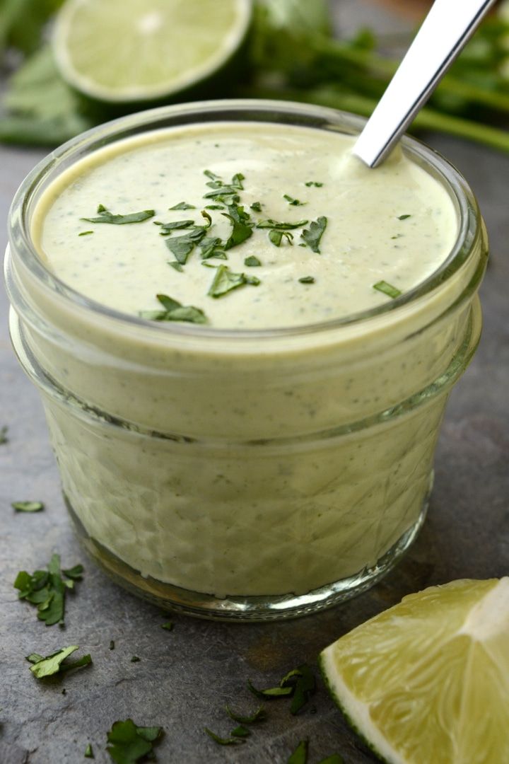 a glass jar filled with dressing next to sliced limes