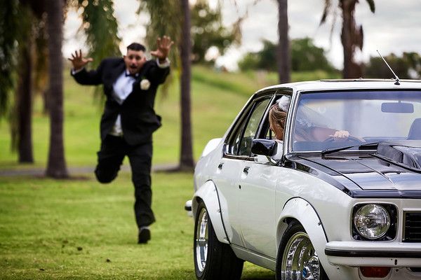 a man in a tuxedo is running towards a car with the hood up